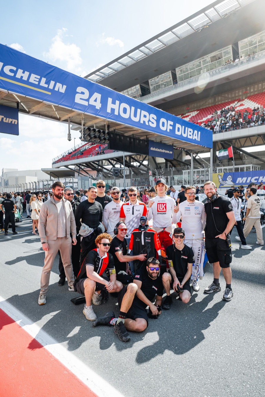 The team and crew together on the grid under the 24 Hours of Dubai bridge, 2026