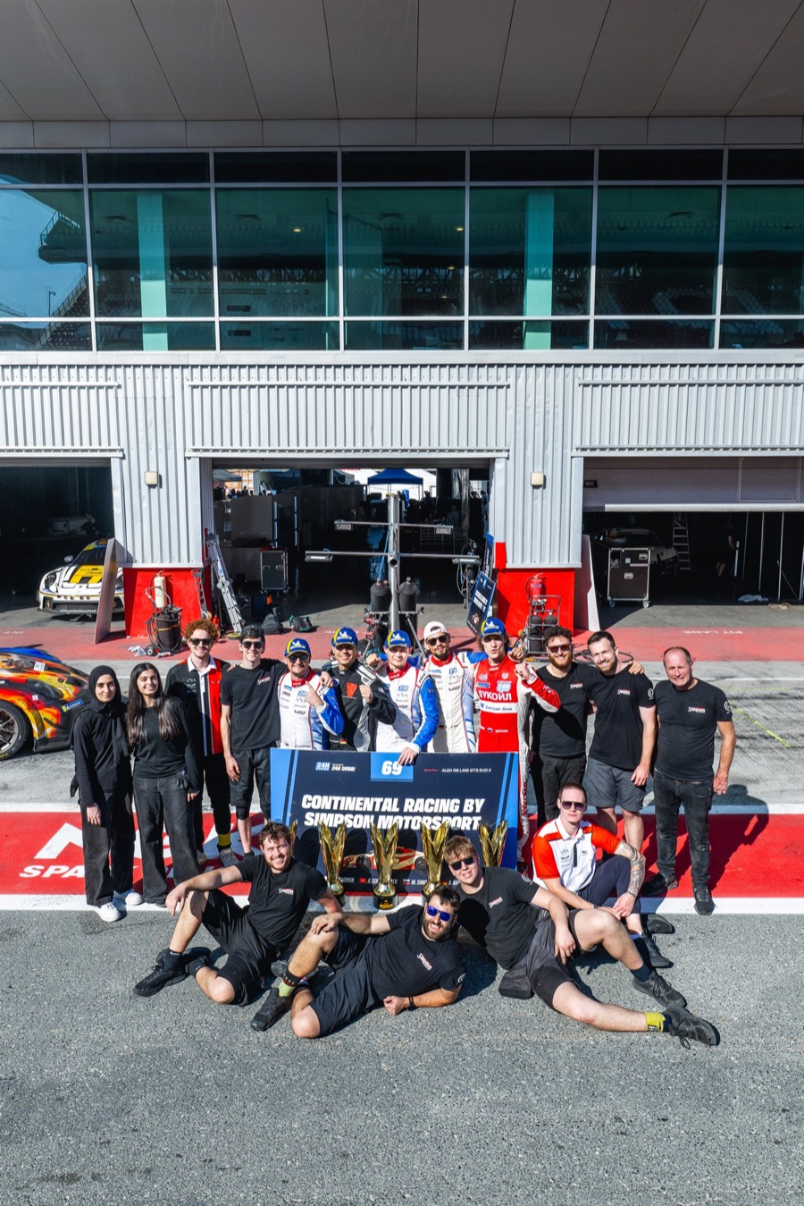 The team with the trophies and the number 69 pit board in front of the garage, Dubai 2026