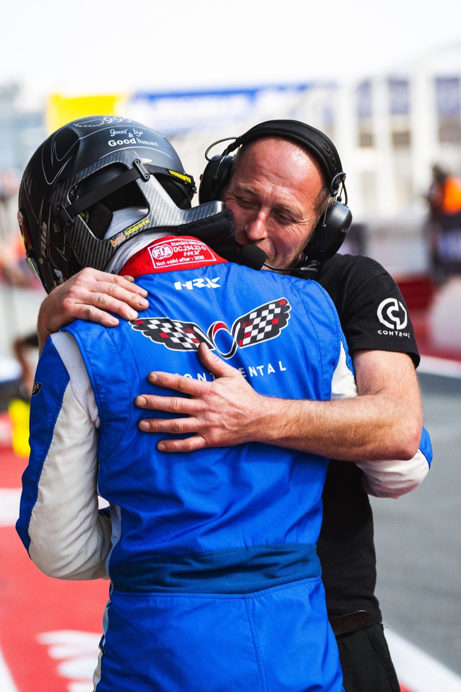 A driver still in helmet held in a long embrace by an engineer in the pit lane, 24 Hours of Dubai 2026