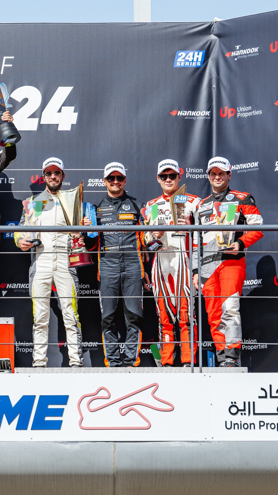 Four drivers with their trophies on the 24H SERIES podium at the Dubai Autodrome