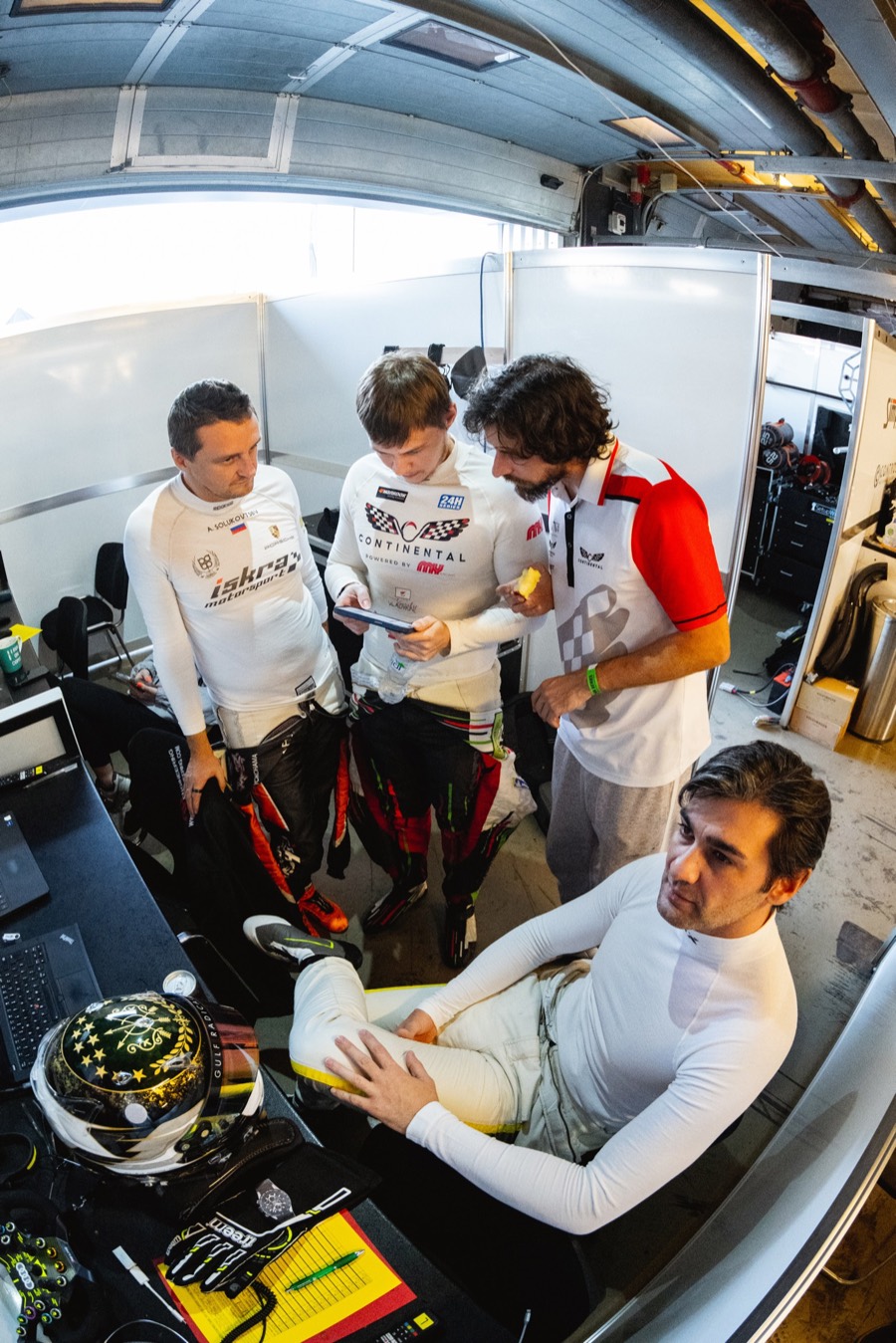 A driver waiting in the seat while three of the crew stand over the sheets in the garage