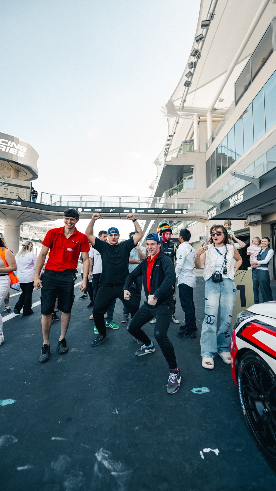 Three of the team caught mid-jump in the pit lane beside the car