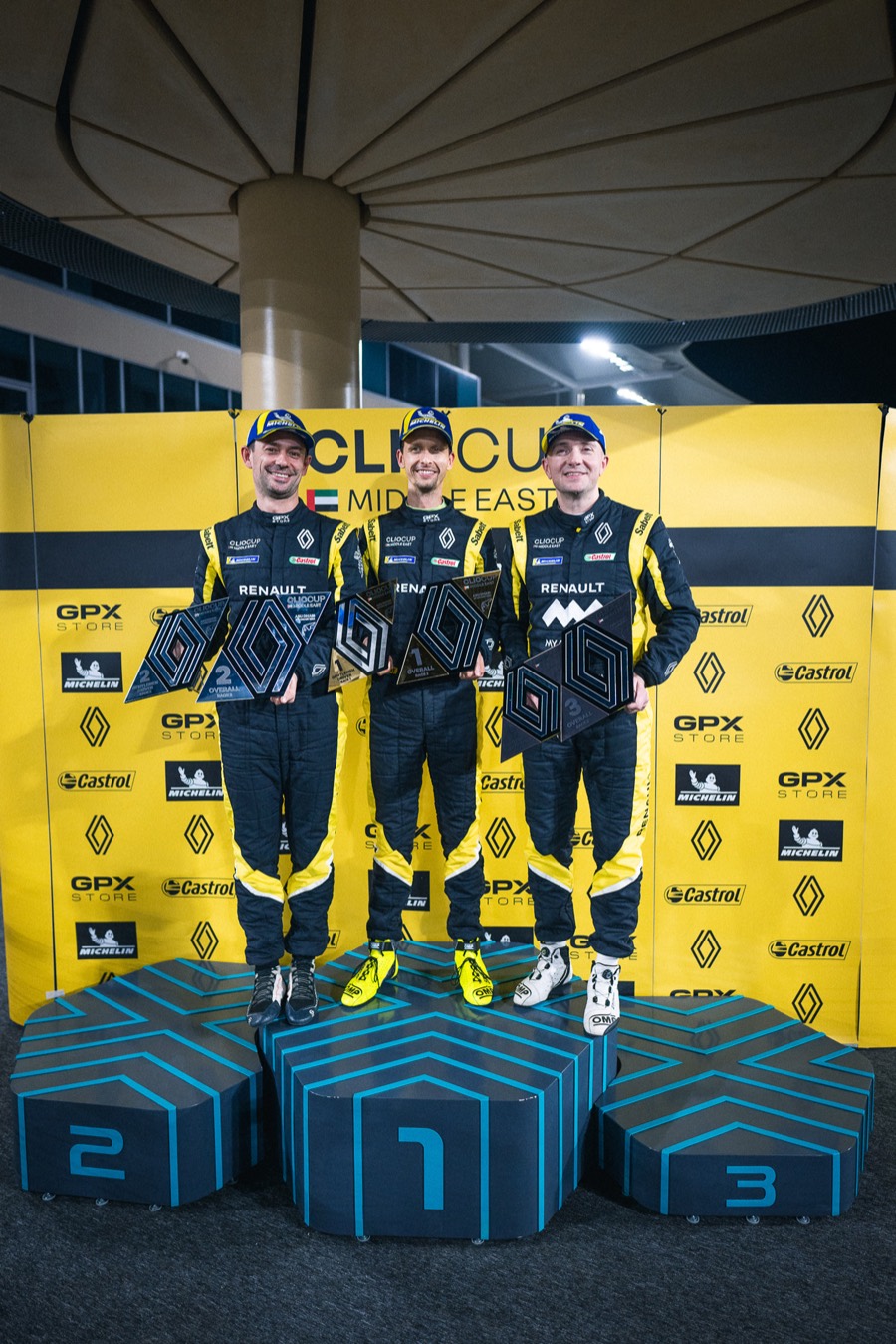 Three drivers on the first three steps of the Clio Cup Middle East podium, trophies held out